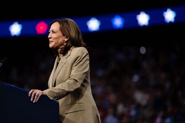 Kamala Harris stands at a lectern, smiling.