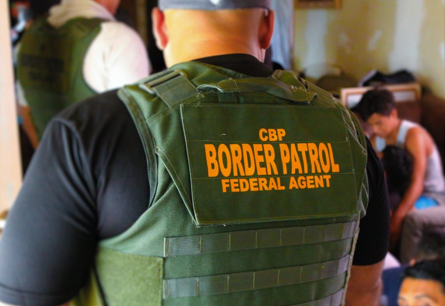 A U.S. Border Patrol agent wearing body armor inspects a residence.